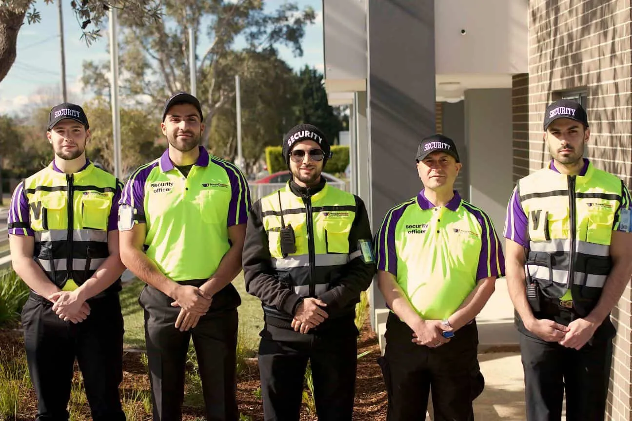 Five uniformed Pinnacle Protection security officers standing outside a client site